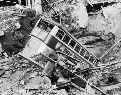 AIR RAID DAMAGE IN BRITAIN DURING THE SECOND WORLD WAR (HU 36188) In the aftermath of a bombing raid, a bus lies in a crater in Balham, South London. Copyright: © IWM. Original Source: http://www.iwm.org.uk/collections/item/object/205087151